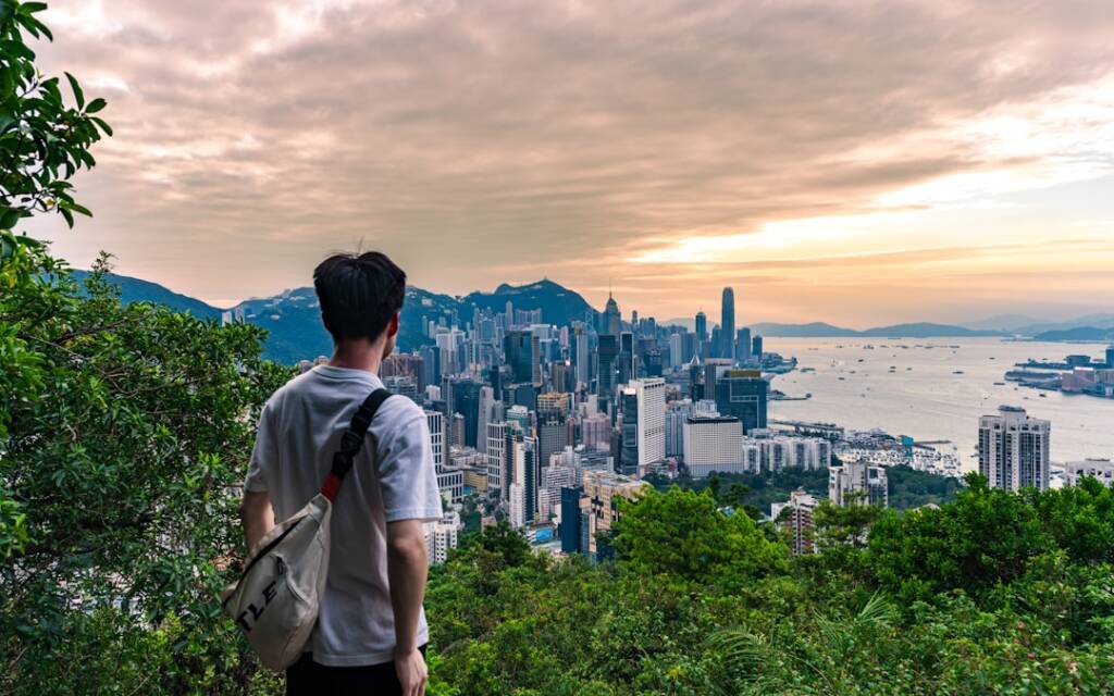 Traveler seen from behind overlooking the Hong Kong skyline at sunset