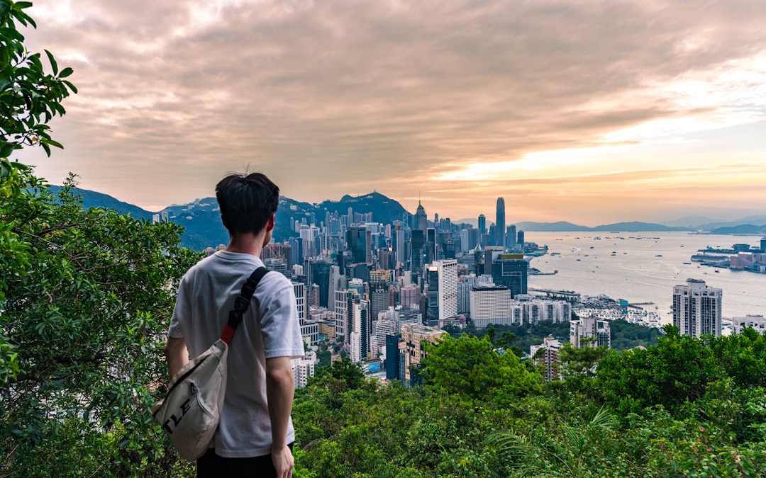 Traveler seen from behind overlooking the Hong Kong skyline at sunset